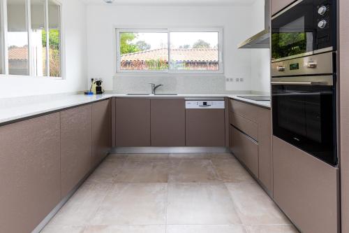 La cuisine est équipée de placards bruns et d'un évier. dans l'établissement Maison Moliets - Proche plage Adrénaline Parc, à Moliets-et-Maa