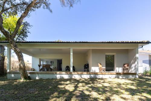 une maison avec une terrasse couverte dotée de chaises et d'un arbre dans l'établissement Maison Moliets - Proche plage Adrénaline Parc, à Moliets-et-Maa