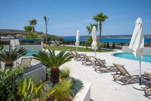 un complejo con piscina, sillas y sombrillas en AmphiMatrion Luxury Apartments en Kalyves