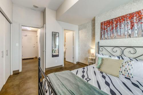 a bedroom with a bed and a painting on the wall at Luxury 2BR Condo - Downtown City Views in Calgary