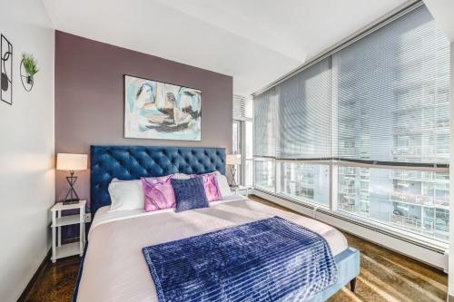 a bedroom with a blue bed and a window at Luxury 2BR Condo - Downtown City Views in Calgary