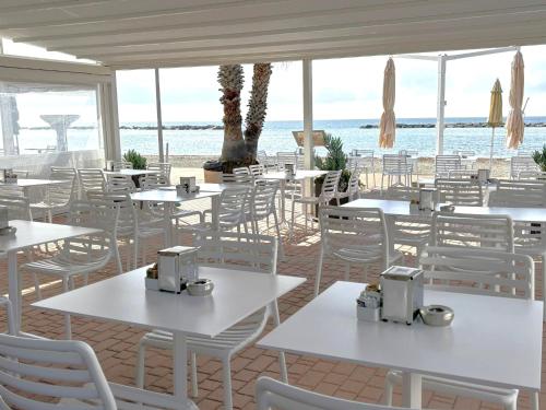 a restaurant with white tables and chairs and the ocean at Hotel Delle Rose in San Bartolomeo al Mare