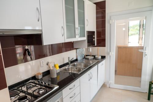 una cucina con mobili bianchi e un lavandino di TURISALENTEJO - ATIVIDADES TURÍSTICAS, LDA a Redondo