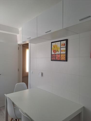 a white kitchen with a white table and chairs at apartamento perto do Santuário in Fátima