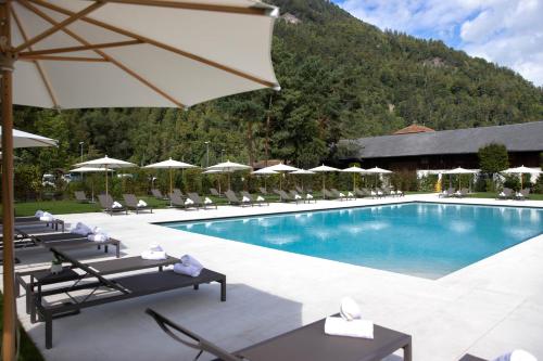 a pool at a resort with chairs and an umbrella at Victoria Jungfrau Grand Hotel & Spa in Interlaken
