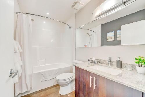 La salle de bains blanche est pourvue de toilettes et d'un lavabo. dans l'établissement Luxury 2BR Condo - King Bed - Stunning City Views, à Calgary