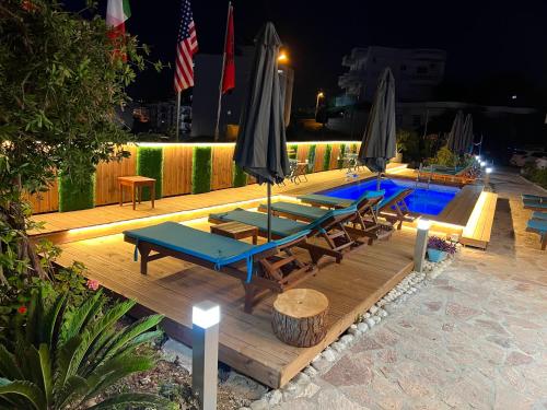 uma piscina com mesas, cadeiras e guarda-sóis em Hotel Two Mermaids Ksamil em Ksamil