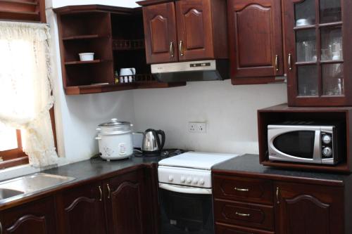 a kitchen with wooden cabinets and a stove and microwave at Natures Bliss Holidays in Ja-Ela