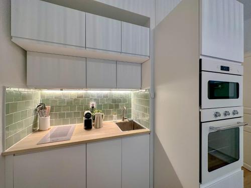 une cuisine avec des armoires blanches et un évier dans l'établissement Appartement T2 Eaux-Bonnes, à Eaux-Bonnes
