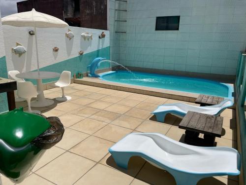 baño con piscina con mesa, mesa y sillas en Pousada Santa Fé en Aracaju