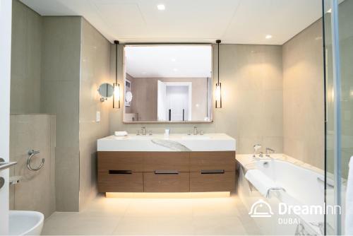 uma casa de banho com um lavatório, uma banheira e um espelho. em Dream Inn - Address Beach Residence - Free Beach Access em Fujairah