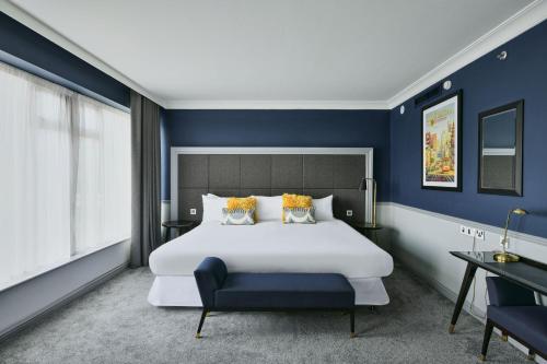 ヒリンドンにあるシェラトン ヒースロー ホテルの青い壁のベッドルーム1室(大きな白いベッド1台付)