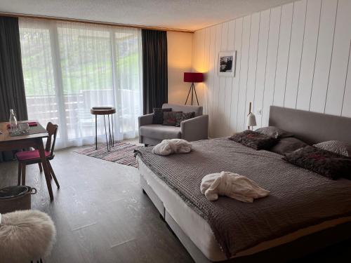Hotel Alfa Superieur - Leukerbad-Therme في لوكرباد: غرفة نوم بسرير وكرسي وطاولة