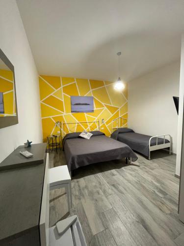 Habitación con 2 camas y pared amarilla. en Perla Marina, en Realmonte