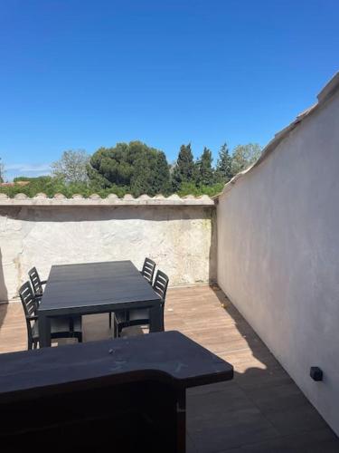 une table noire et des chaises sur une terrasse dans l'établissement Maison de ville avec terrasse., à Marseillan