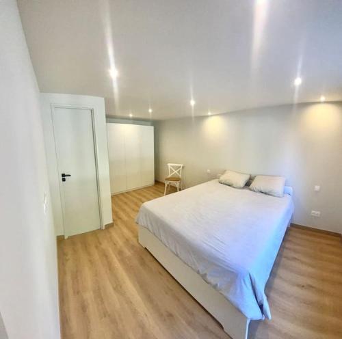 une chambre avec un grand lit blanc et une chaise dans l'établissement Maison de ville avec terrasse., à Marseillan