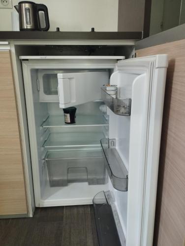 un réfrigérateur vide avec sa porte ouverte dans une cuisine dans l'établissement Studio Terrasse Privée Jardin Air conditionné, à Aix-en-Provence