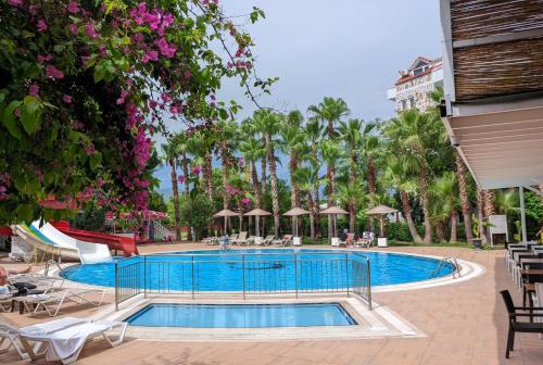 una piscina en un complejo con mesas y sillas en UK Hotel Kiriş en Antalya