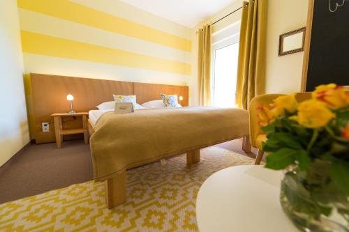 a hotel room with a bed and a vase of flowers at Das Eisenberg in Sankt Martin an der Raab