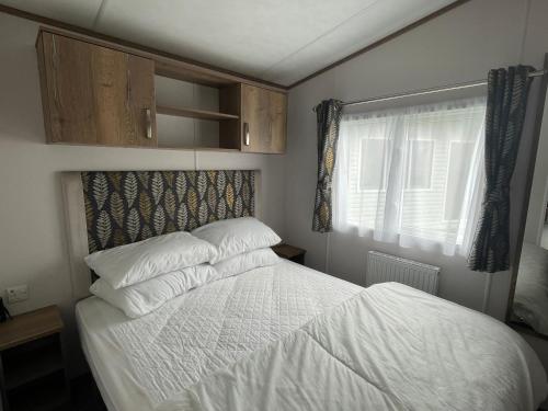 a bedroom with a bed with white sheets and a window at Robin Hood Caravan Park in York