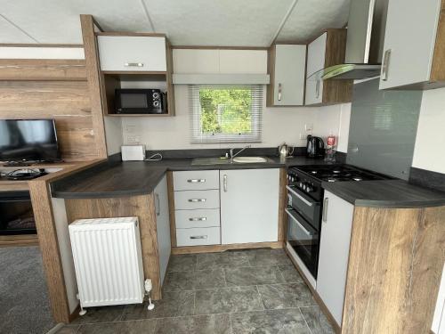 a kitchen with white cabinets and a stove top oven at Robin Hood Caravan Park in York