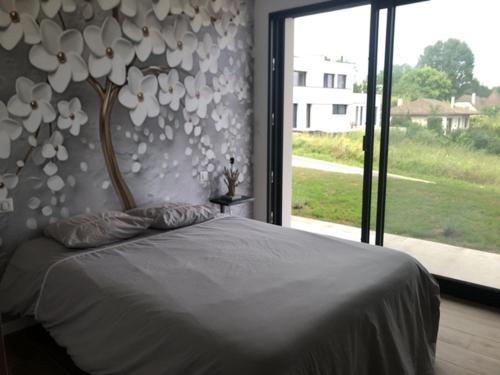 een slaapkamer met een groot bed met een groot raam bij La Villa in Brive-la-Gaillarde