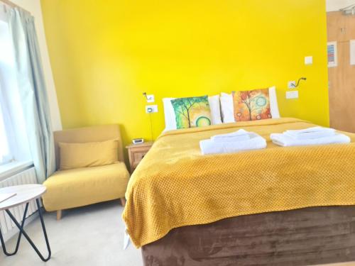 a yellow bedroom with a bed and a chair at Torland Seafront Hotel - all rooms en-suite, free parking, wifi in Paignton