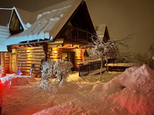 a log cabin in the snow at night at Domki Majerczykówka 29a in Poronin