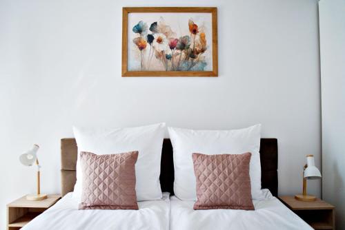 1 cama con 2 almohadas y una pintura en la pared en Apartament Bulwary 3, en Oświęcim
