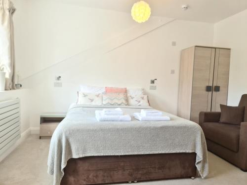 um quarto branco com uma cama e uma cadeira em Torland Seafront Hotel - all rooms en-suite, free parking, wifi em Paignton