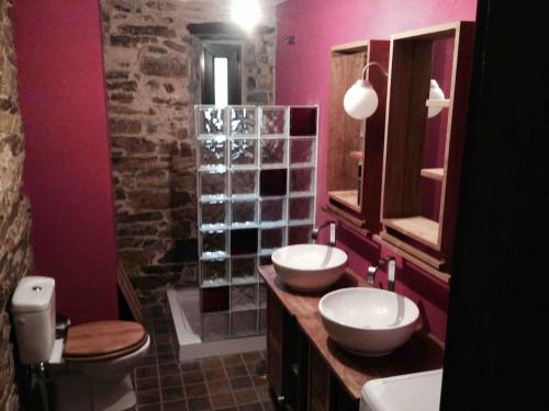 a pink bathroom with two sinks and a toilet at O Recuncho de Doiras in Ferreiravedés