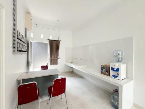 a kitchen with two red chairs and a counter at RedDoorz at Griya Martha Sumber Solo in Bonorejo
