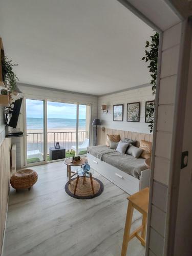 sala de estar con sofá y vistas al océano en Week end romantique FACE A LA MER, en Narbonne-Plage
