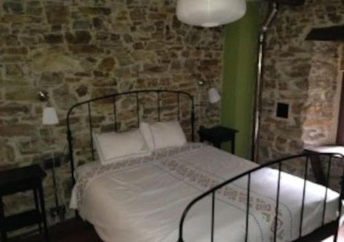 a bedroom with a bed and a stone wall at O Recuncho de Doiras in Ferreiravedés