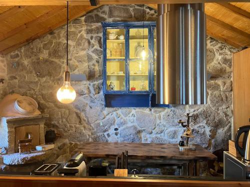 a kitchen with a stone wall with a window at Casa do Avô in Cinfães