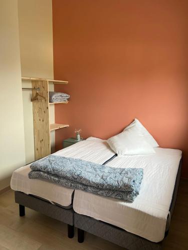 - une chambre dotée d'un lit avec un mur orange dans l'établissement eco nature, gite à la ferme, à Vendays-Montalivet