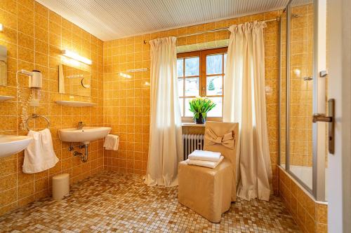 a yellow tiled bathroom with a sink and a window at Gästehaus Daheim in Riezlern