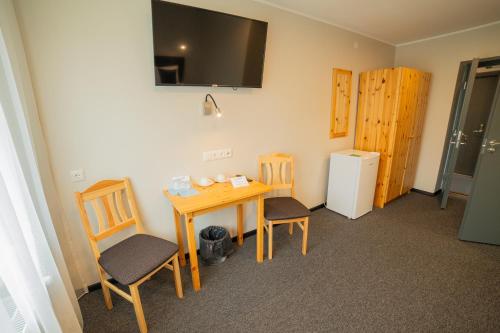 KuremaaにあるKuremaa Külalistemajaのテーブルと椅子、冷蔵庫が備わる客室です。