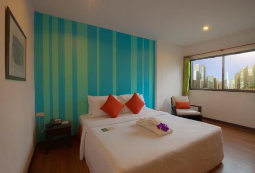 a bedroom with a large bed with a green wall at Woraburi Sukhumvit Hotel in Bangkok