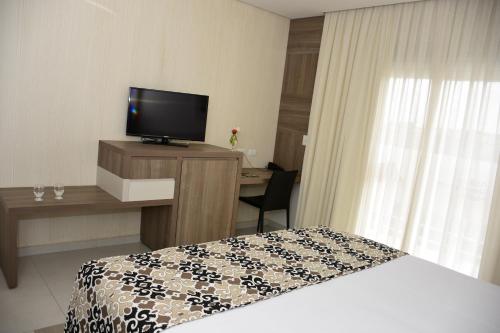 a hotel room with a bed and a desk with a television at Atibaia Residence Hotel & Resort in Atibaia