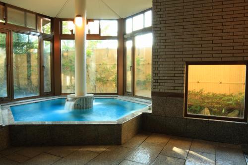 bañera de hidromasaje en una habitación con ventanas en Yabukiso en Yamanakako