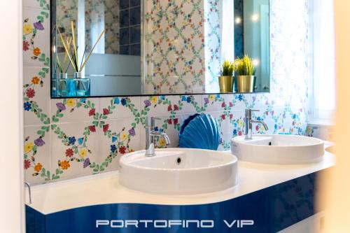 two sinks in a bathroom with floral wallpaper at Paraggi Apartment by PortofinoVip in Paraggi