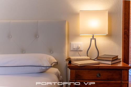 a lamp on a table next to a bed with books at Paraggi Apartment by PortofinoVip in Paraggi
