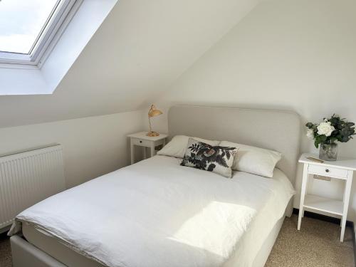 um quarto com uma cama branca com duas mesas de cabeceira em The Barn em Chichester