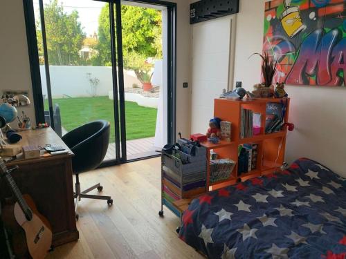 - une chambre avec un lit et un bureau avec une guitare dans l'établissement Maison de vacances piscine intérieure La Rochelle, à La Rochelle