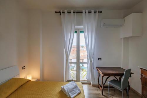 a bedroom with a bed and a desk and a window at La Fenice Suites Sardinia in Quartu SantʼElena