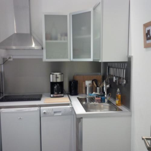 une cuisine avec des armoires blanches et un évier dans l'établissement Le Malraux, à Sarlat-la-Canéda