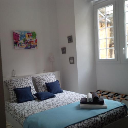 une chambre avec un lit avec des oreillers bleus et une fenêtre dans l'établissement Le Malraux, à Sarlat-la-Canéda