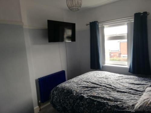 a bedroom with a bed and a window with blue curtains at Entire House in Belfast