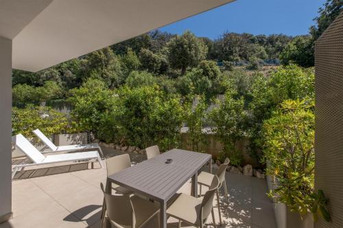 a patio with a table and chairs and trees at Zlatni Zalaz,Apartments,Supetarska Draga in Supetarska Draga